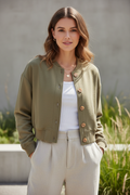 Woman wearing khaki cropped button-front bomber jacket in casual outdoor setting